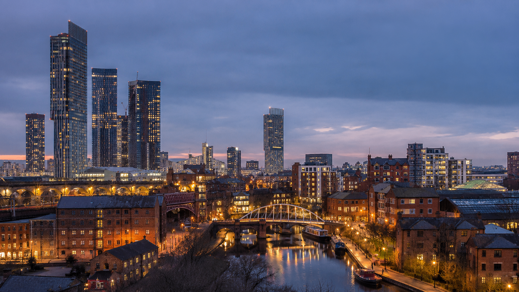 Manchester city-centre skyline with modern towers and red-brick buildings.