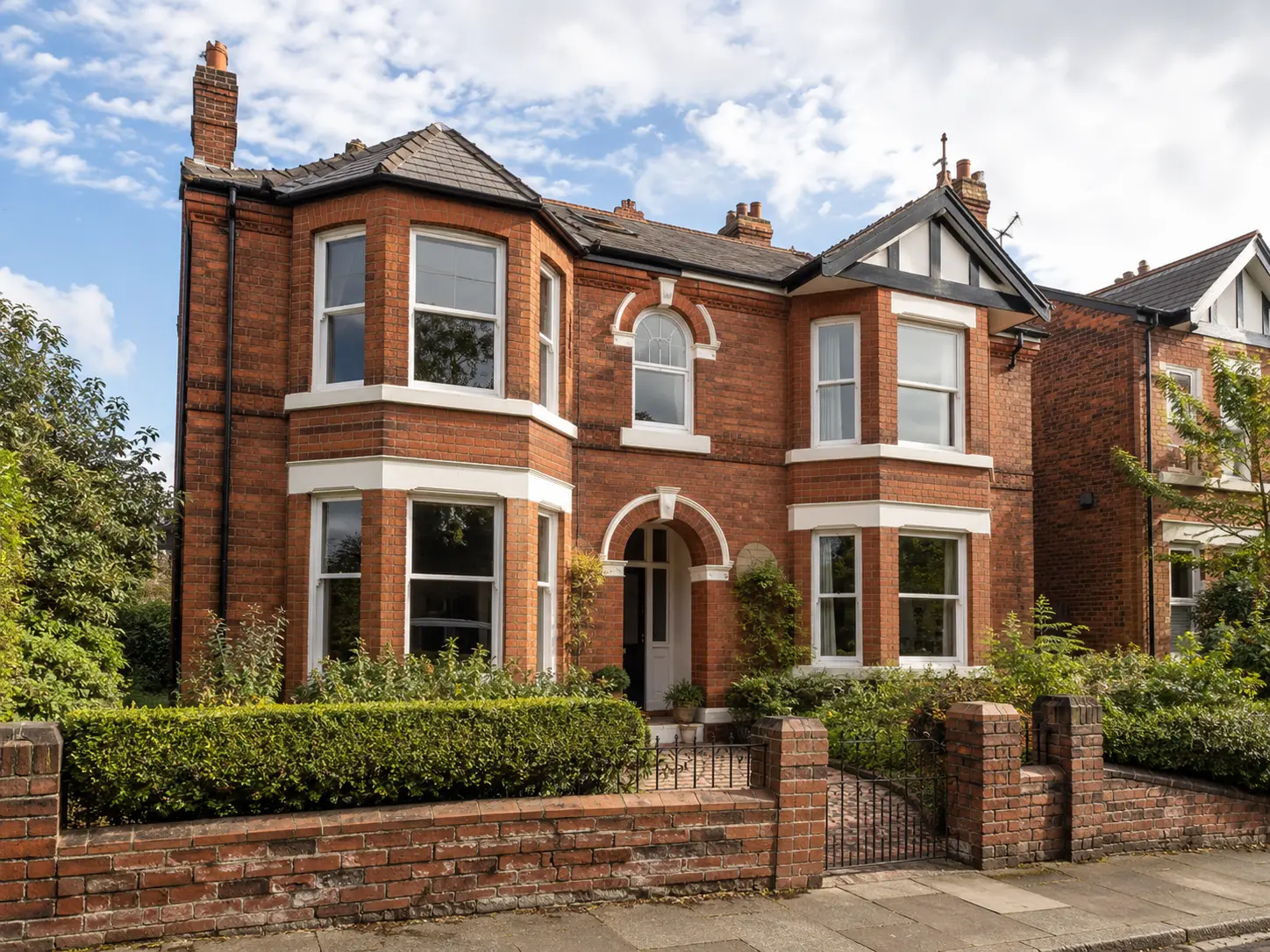 Substantial red-brick period house with bay windows and a front garden.
