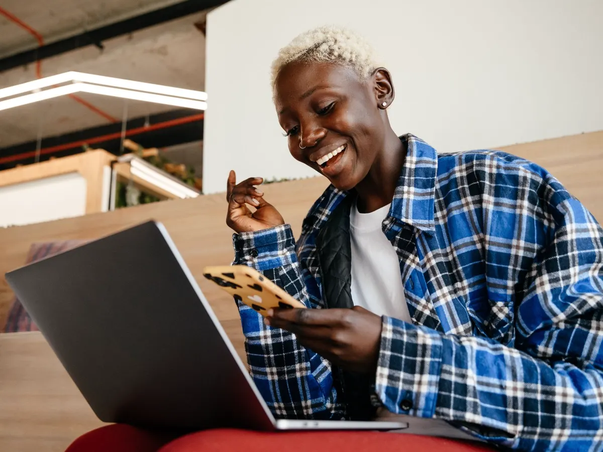 Person replying to messages on a phone beside a laptop