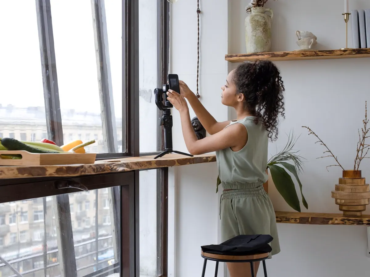 A camera on a stand photographing a room by a bright window