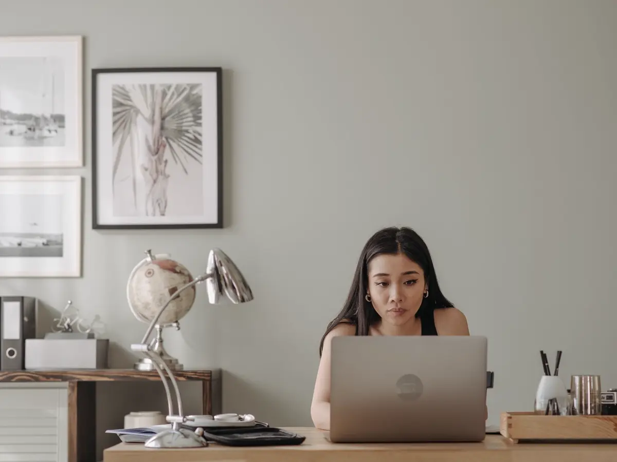 A person reviewing information on a laptop at a tidy home desk