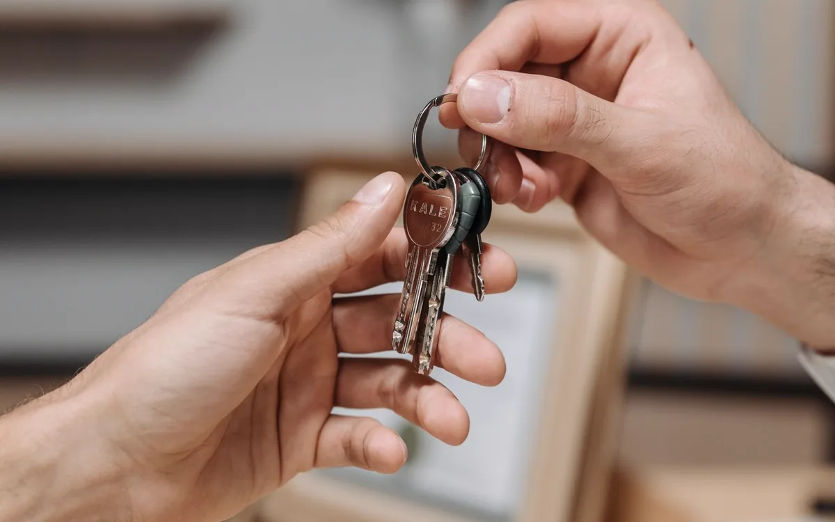A set of keys being handed from one person to another indoors.